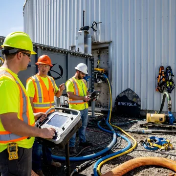 Industrial tank maintenance team monitoring robotic cleaning