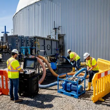 Technicians operating a robotic tank cleaning system