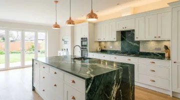 Bold green granite countertop paired with white shaker cabinets in luxury kitchen