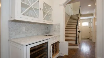 Custom built-in wet bar cabinet with integrated sink quartz countertop and glass-front uppers