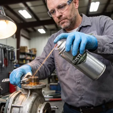 Maintenance worker spraying penetrating oil on equipment
