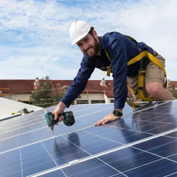 Technician installing solar panels with professional tools and safety equipment