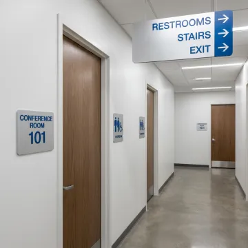 ADA and wayfinding signs in a commercial hallway