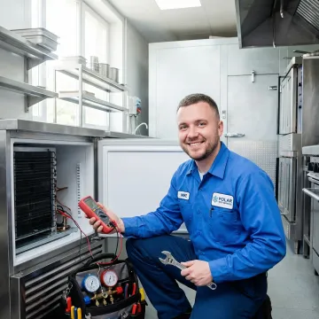 Commercial refrigeration repair technician servicing walk-in cooler in Brenham TX business