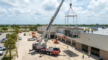 Spinning Crane Works boom crane performing rooftop HVAC unit placement at height