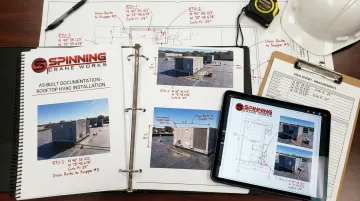 HVAC technician reviewing rooftop unit as-built documentation with installation photographs