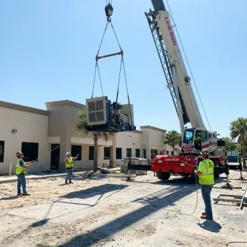 Crane lifting heavy equipment in Plant City