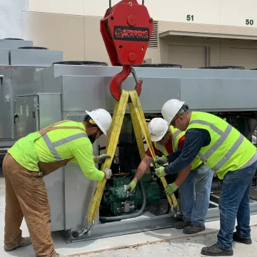 Crane crew rigging HVAC unit for lift