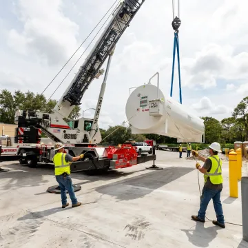 Crane and rigging crew lifting heavy equipment