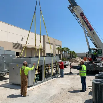 Crane crew preparing HVAC equipment for rooftop lift