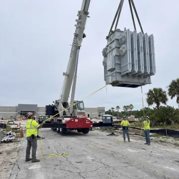 Crane lifting heavy machinery at a Florida job site