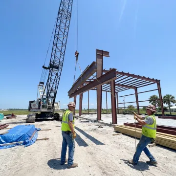 Commercial crane lifting structural steel on a Florida jobsite