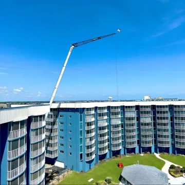 Crane crew preparing HVAC equipment for rooftop lift