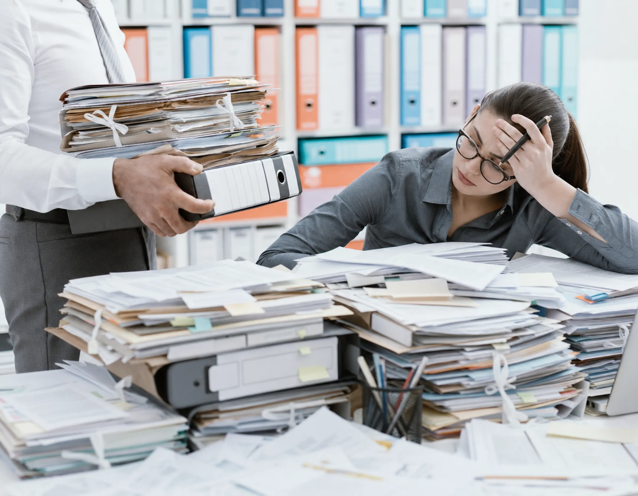 Case manager reviewing client files in disorganized paper-based office setting
