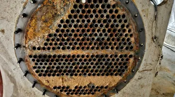 Corroded chiller tube sheet showing pitting channeling and rust deposits at tube ends