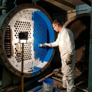 Technician applying protective coating to industrial equipment