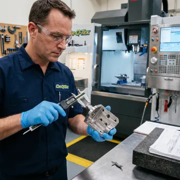Technician inspecting a precision CNC-machined metal part