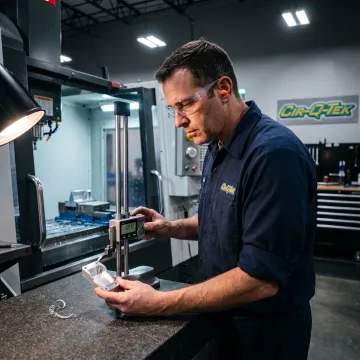 Technician inspecting a machined precision part