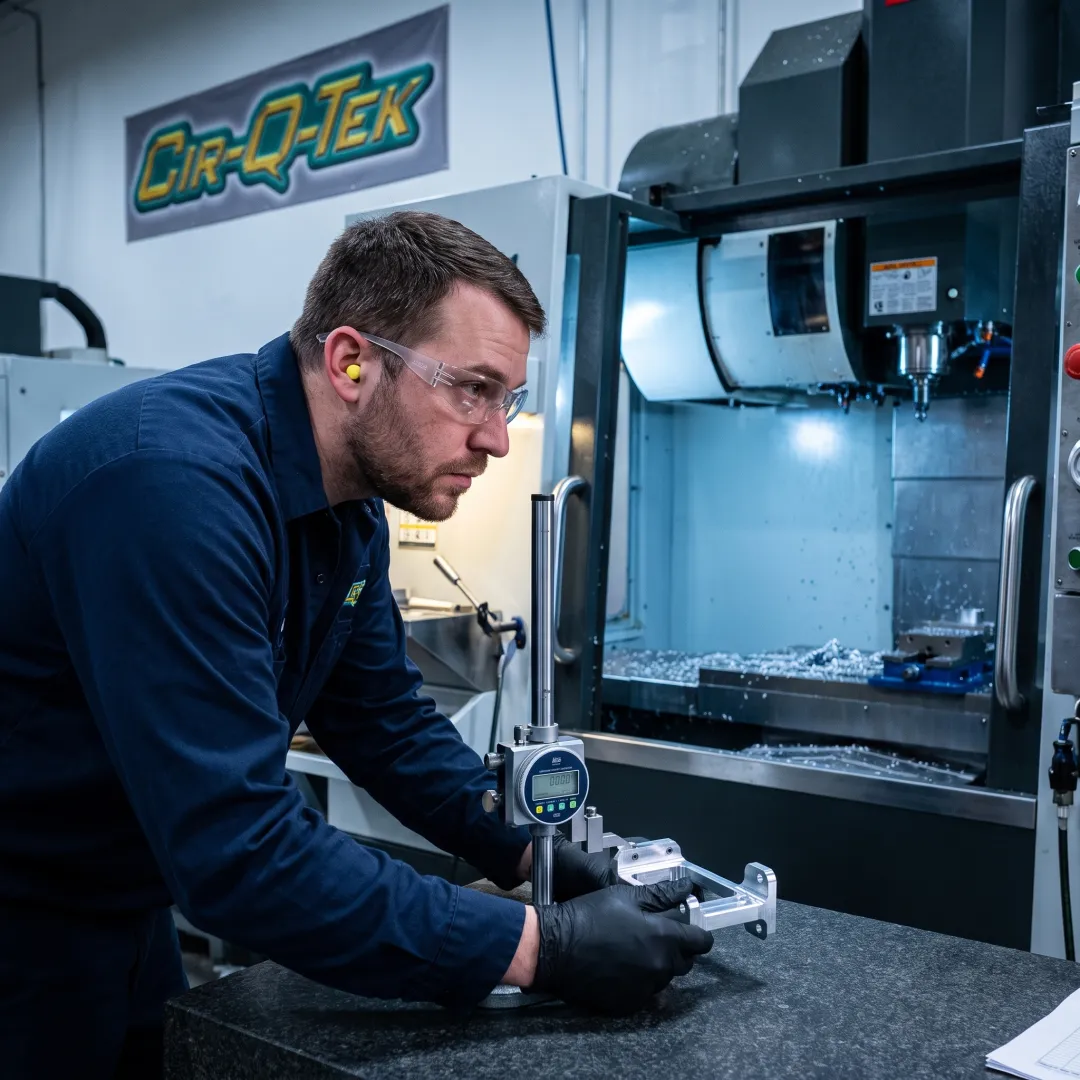 Technician inspecting a machined metal part
