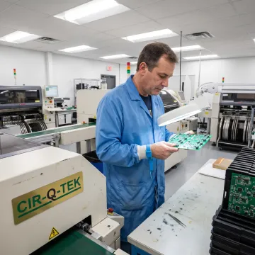 Technician inspecting a populated circuit board
