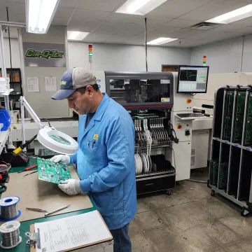 Technician inspecting a populated circuit board