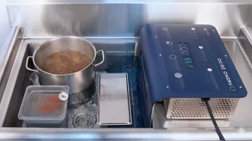 Commercial kitchen staff monitoring soup temperature during rapid cooling process