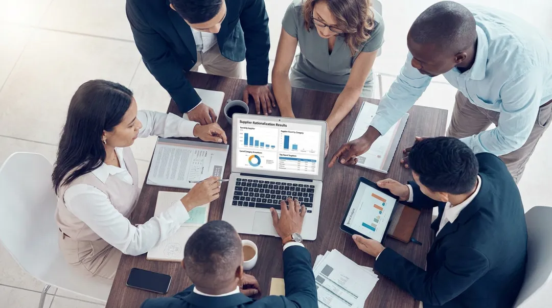 Mid-market procurement team reviewing supplier consolidation results on analytics dashboard