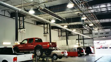 Auto dealership service bay with ceiling-mounted infrared tube heaters installed overhead