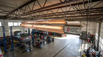 Ceiling-mounted radiant tube heater installed in commercial vehicle service bay