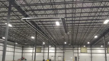 Radiant infrared tube heater mounted in large commercial warehouse with high bay ceiling