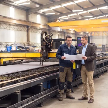 Fabrication manager reviewing laser cutting equipment plans