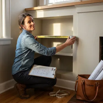 Cabinet designer measuring a living room alcove for built-in units