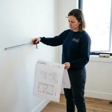 Designer measuring bedroom for custom wardrobe plans