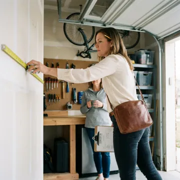 Designer measuring garage for custom cabinets