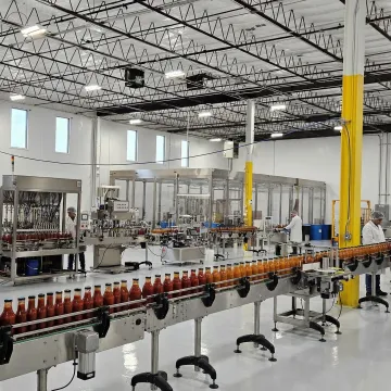 Modern sauce manufacturing facility with stainless steel equipment and bottling line