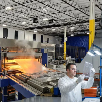 Thermoforming machine creating custom plastic packaging in production facility