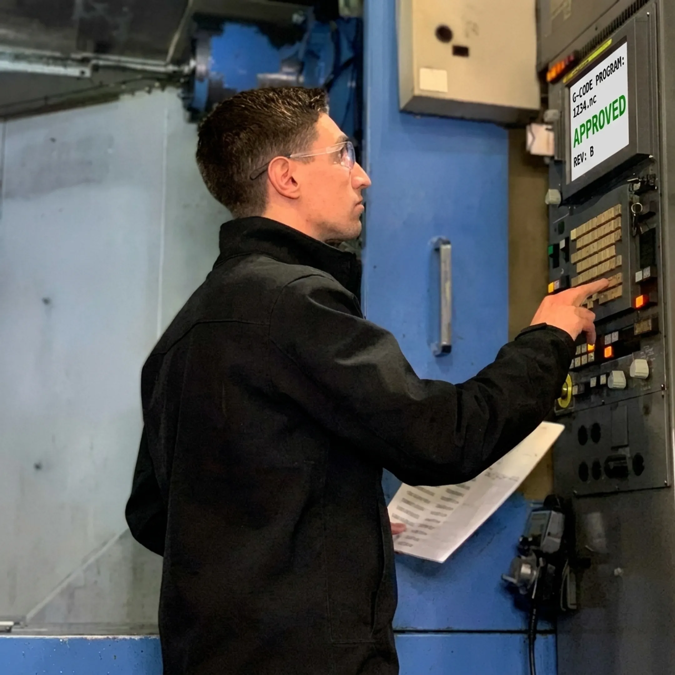 CNC operator reviewing verified G-code revision at machine tool control