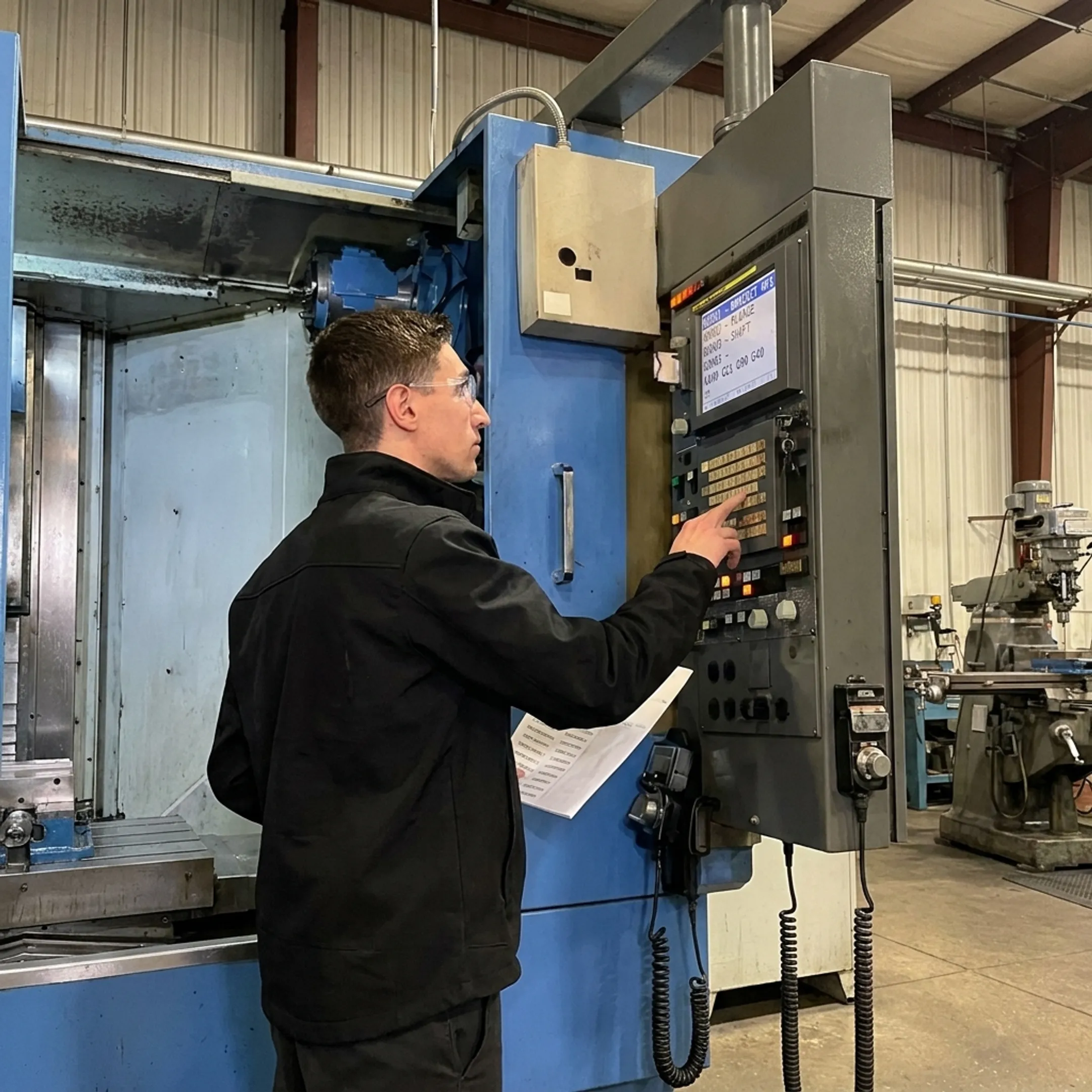 CNC machinist using shop floor management software at machine control terminal