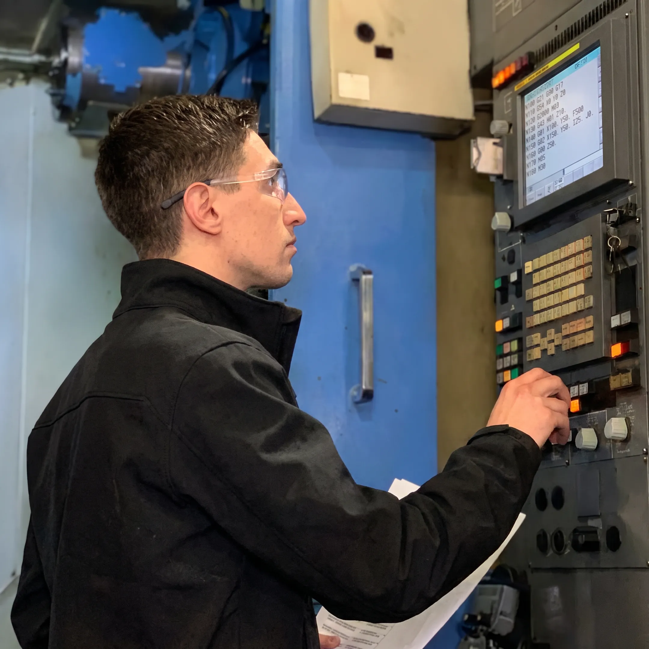 CNC machinist verifying secure program transfer at machine control
