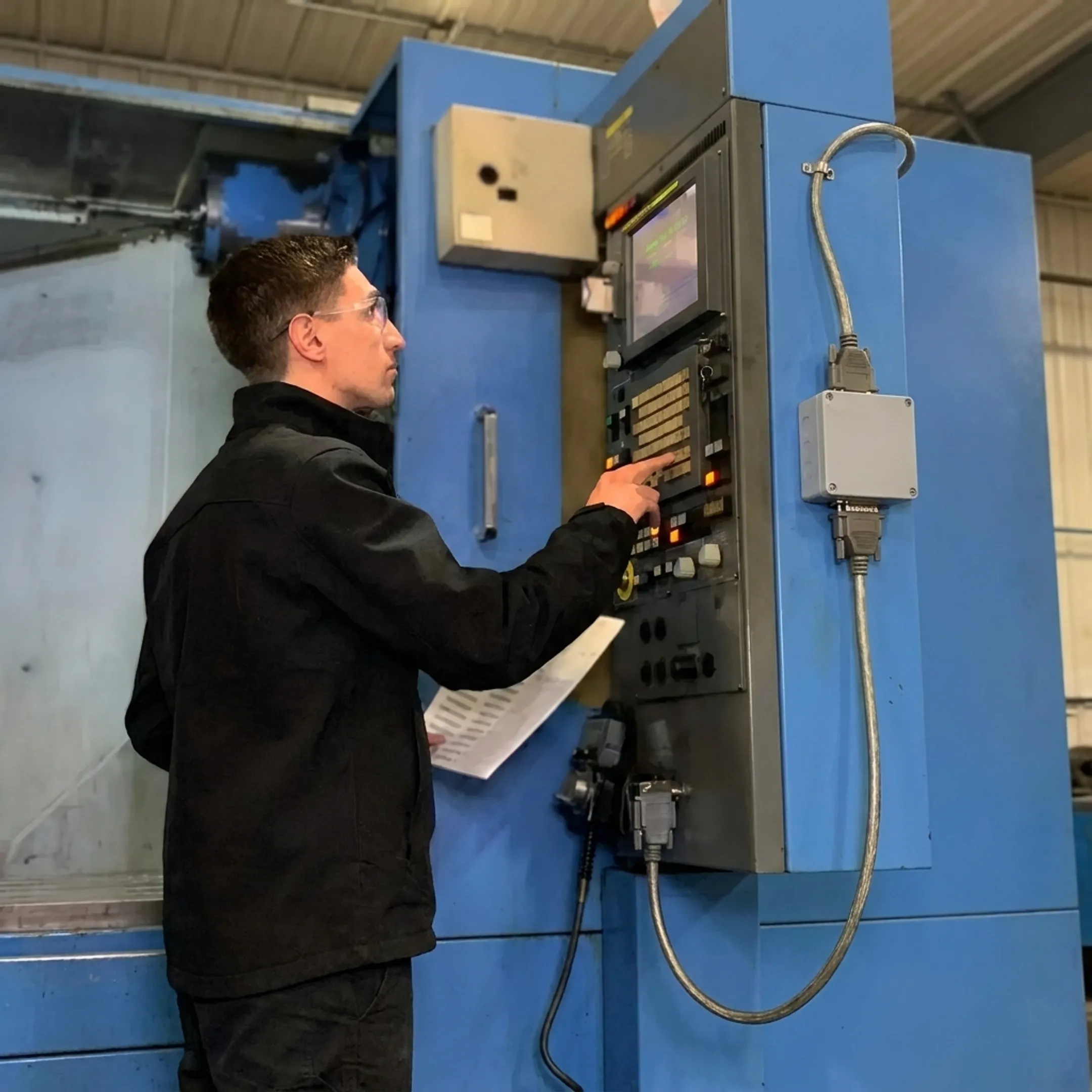 CNC technician setting up secure serial DNC file transfer on machine control