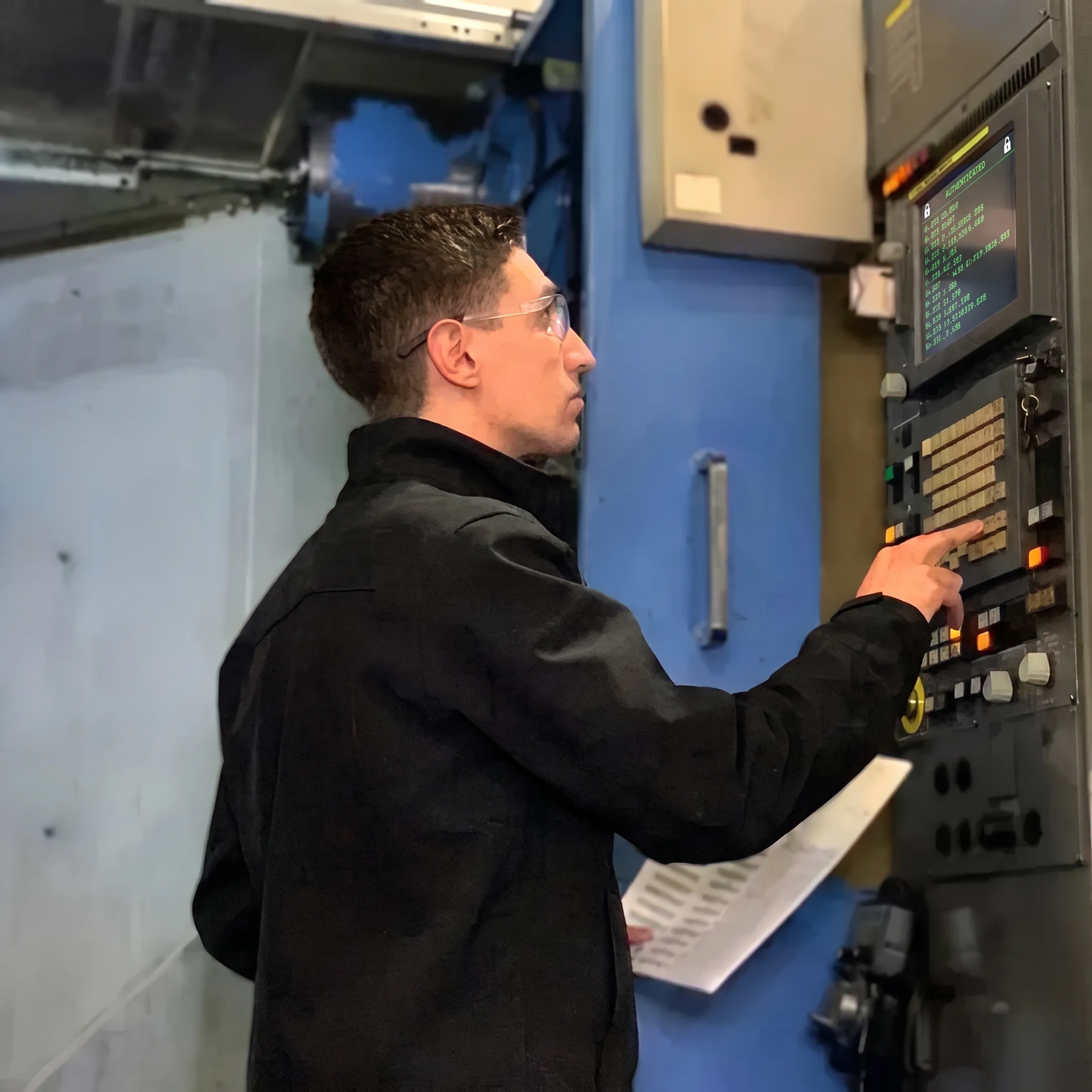 Machinist operating CNC milling center with secure program on screen