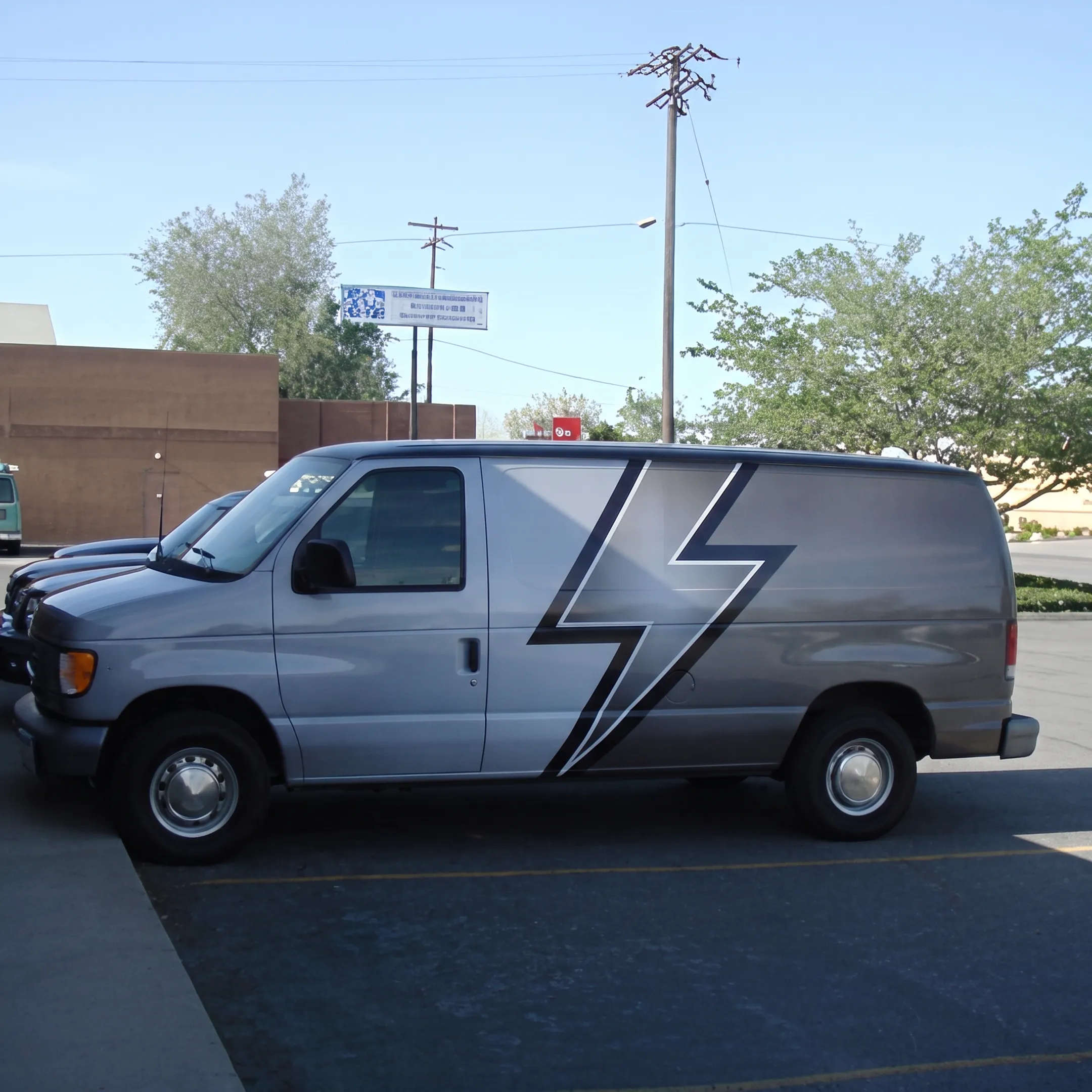 Wrapped electrical contractor van with branded graphics parked near a commercial jobsite