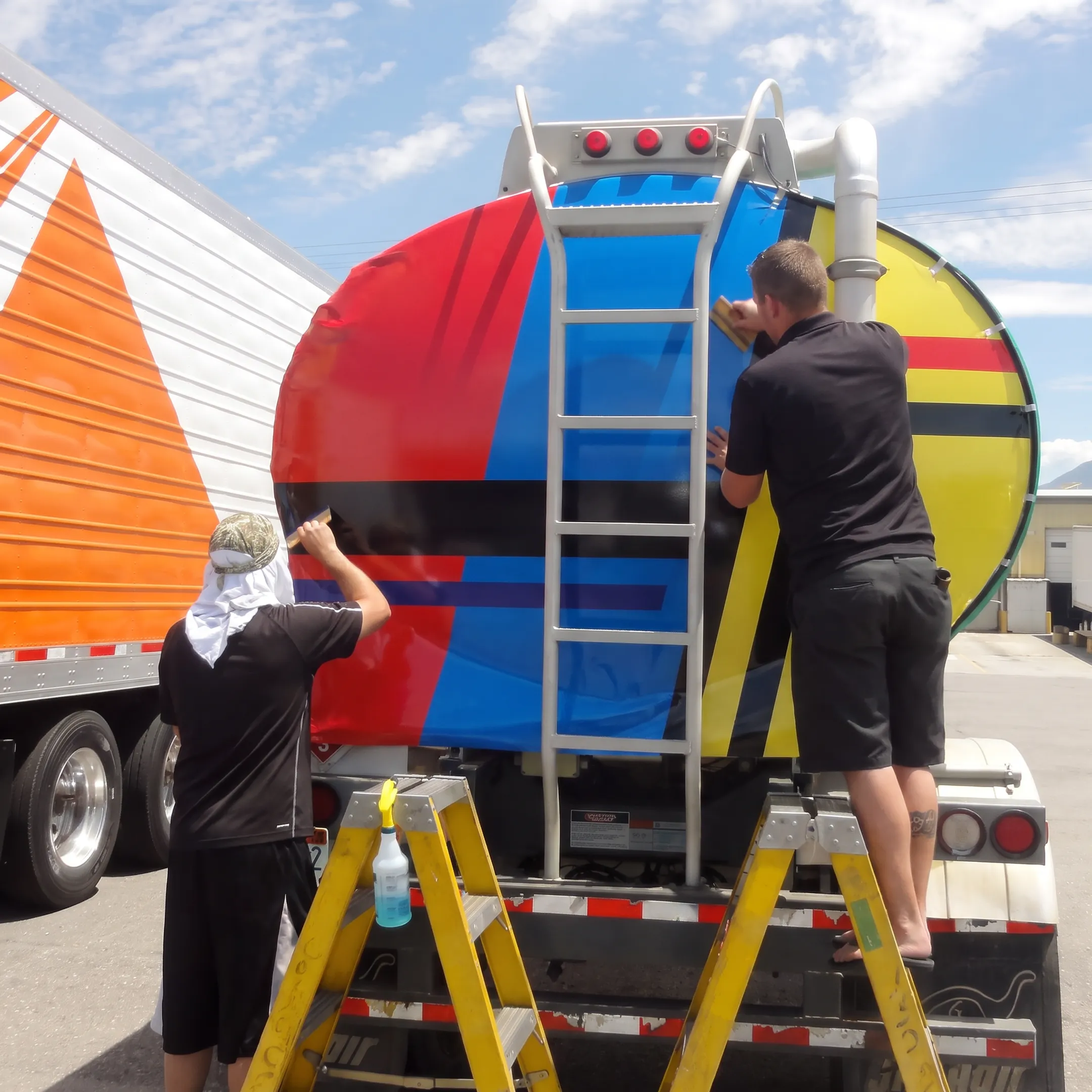 Installer applying branded vinyl graphics to a tow truck