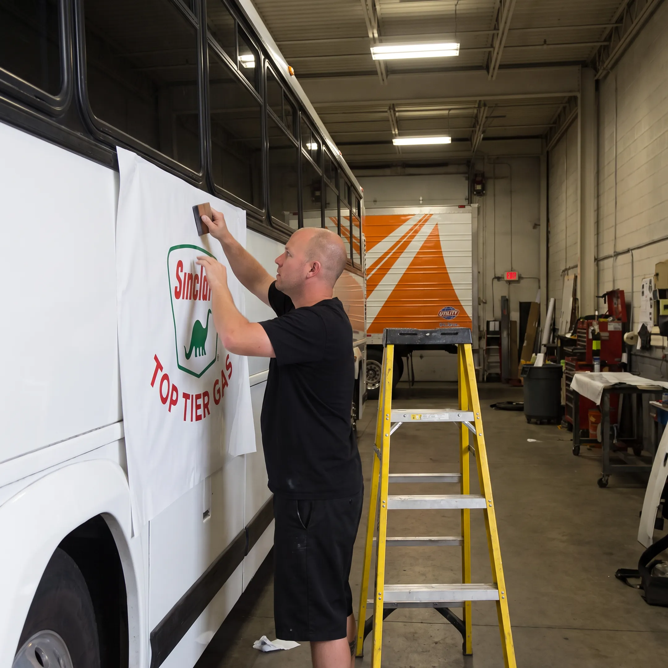 Installer applying custom vinyl graphics to a branded bus