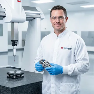 CNC machinist inspecting a titanium orthopedic implant component with precision measurement tools