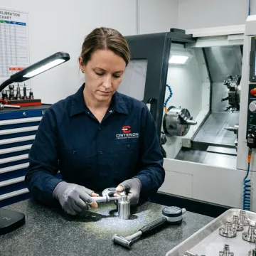 Machinist inspecting a precision CNC turned component