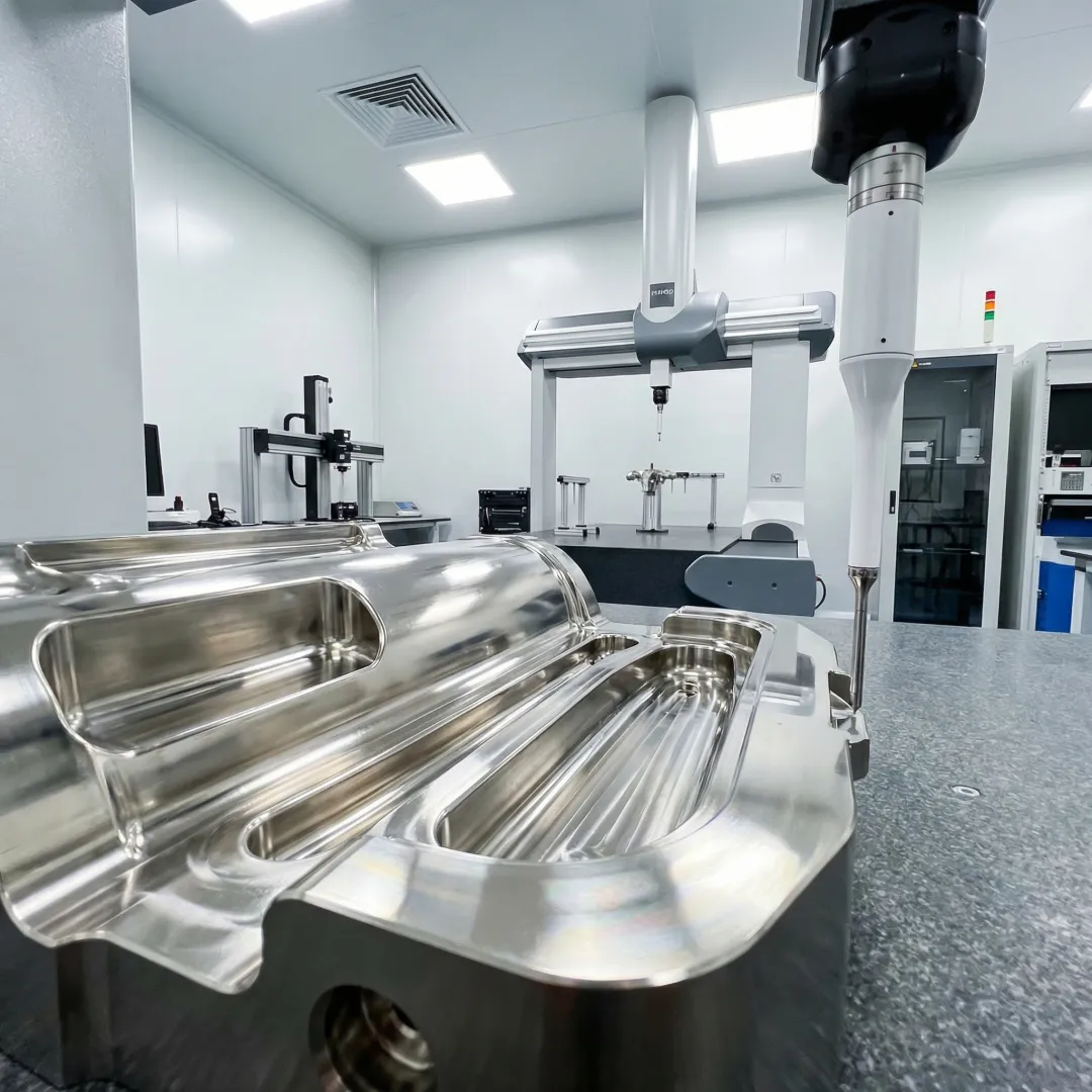 Finished Inconel aerospace component next to a CMM inspection probe in a precision machine shop