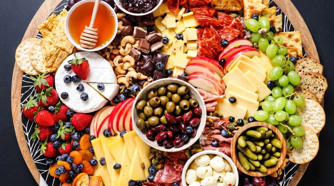 Colorful charcuterie board spread with assorted meats cheeses crackers and fresh fruits