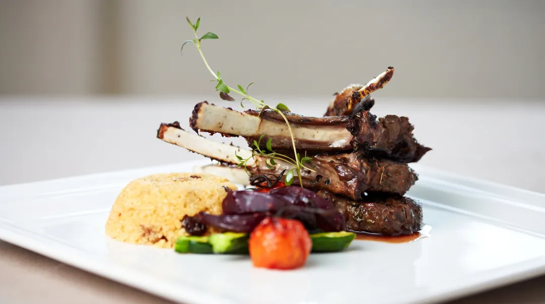 Elegant plated dinner service showing composed entree with protein vegetables and garnish on white china