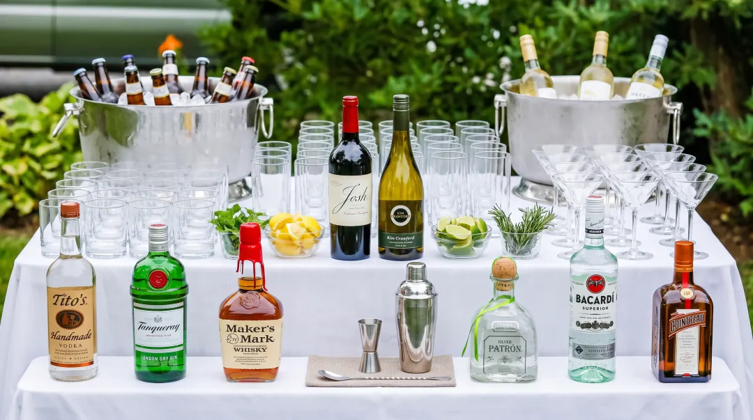Wedding reception bar display with call-brand liquor bottles wine selections and cocktail setup